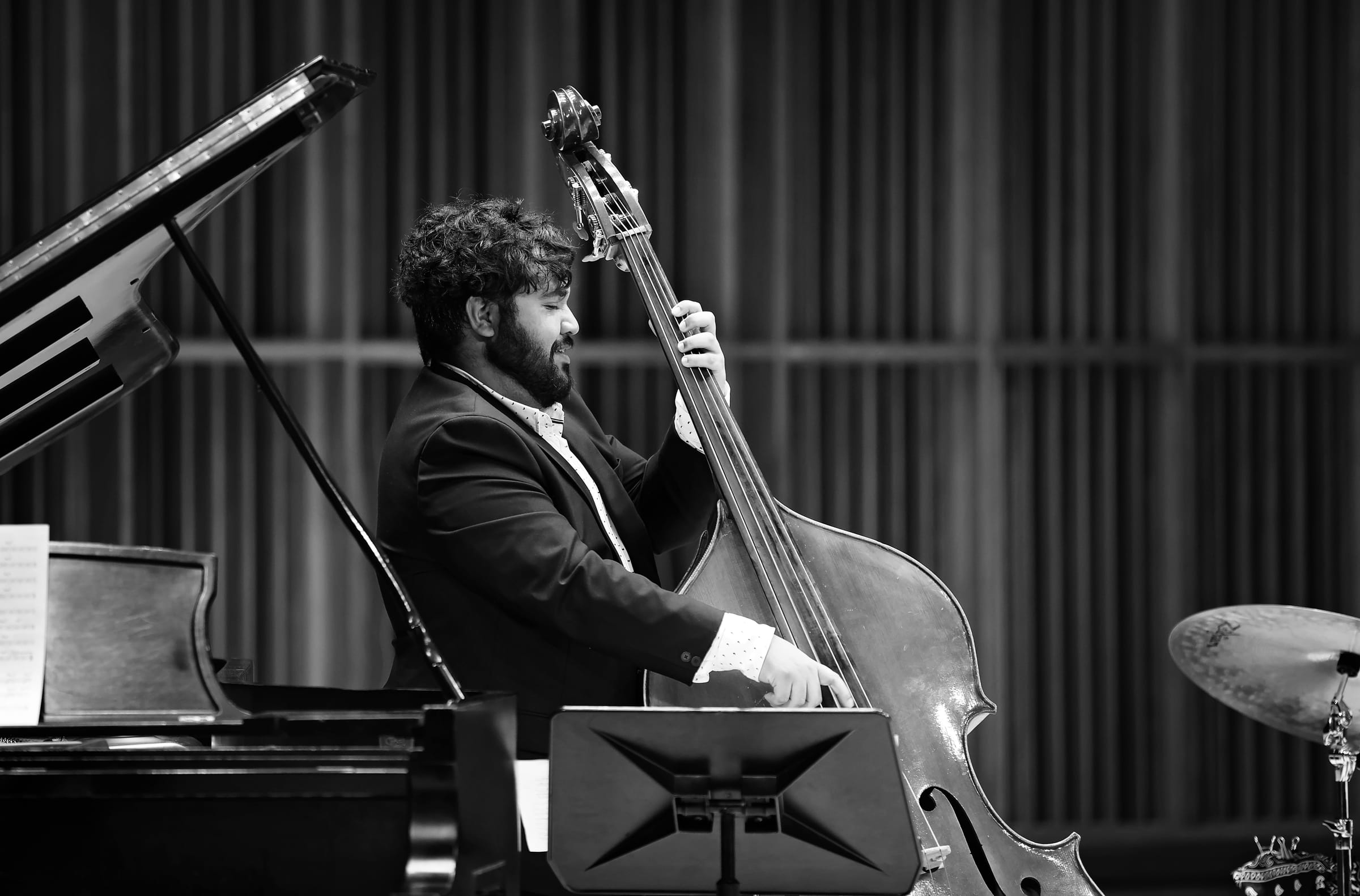 Michael Santos performing on upright bass beside a grand piano